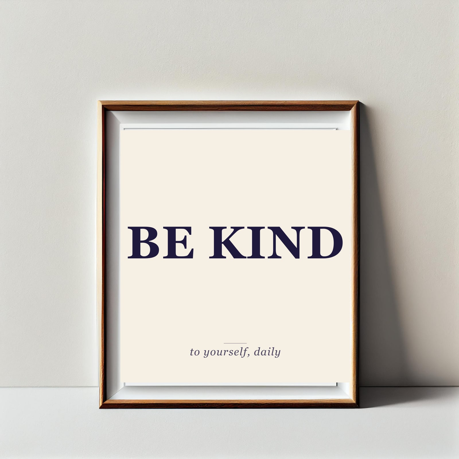 Etsy quote print mockup: BE KIND headline with the description "to yourself, daily" in italic, framed in oak